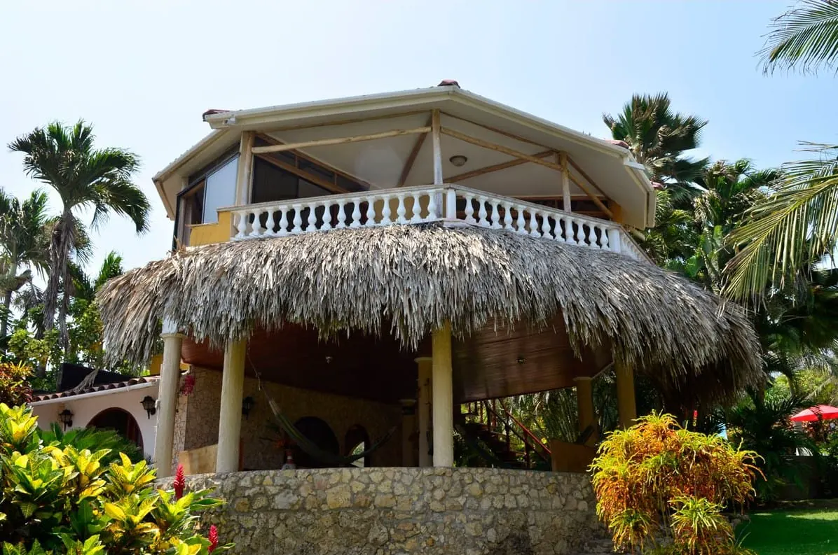 Kiosco de dos niveles con techo de palma y balcón blanco