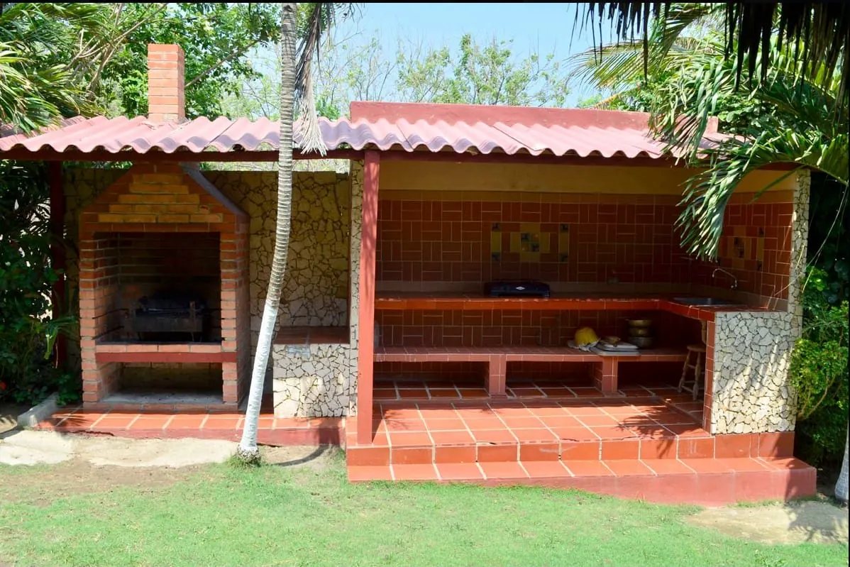 Cocina exterior con parrilla de ladrillo y mesones de baldosa